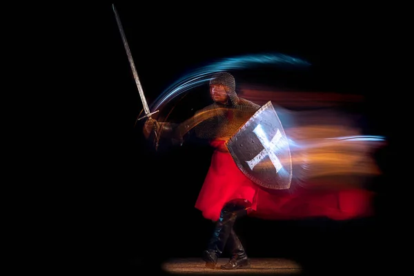 Portret brutalnego poważnego mężczyzny, średniowiecznego rycerza lub wojownika w zbroi i łańcuszku walczącego na ciemnym tle w neonowym świetle mieszanym. Sztuka, historia, kreatywność — Zdjęcie stockowe