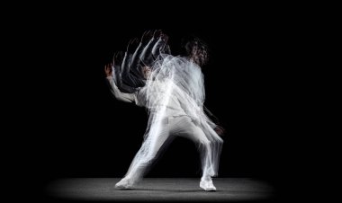 Genç bir adam, hip-hop dansçısı, karanlık arka planda sroboskop etkisi ile izole edilmiş hareket ediyor. Gençlik kültürü, hip-hop, hareket, tarz ve moda, aksiyon.