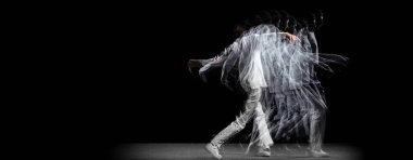 Genç bir adam, hip-hop dansçısı, karanlık arka planda sroboskop etkisi ile izole edilmiş hareket ediyor. Gençlik kültürü, hip-hop, hareket, tarz ve moda, aksiyon.