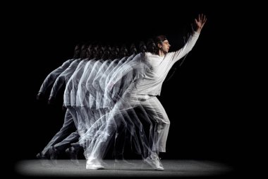 Genç bir adam, hip-hop dansçısı, karanlık arka planda sroboskop etkisi ile izole edilmiş hareket ediyor. Gençlik kültürü, hip-hop, hareket, tarz ve moda, aksiyon.