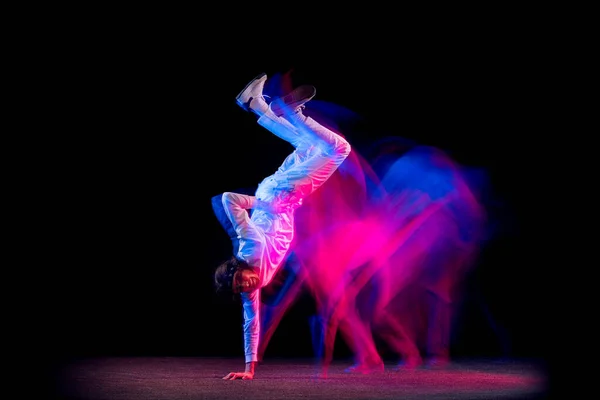Svoboda. Dynamický portrét mužské hip-hopové tanečnice tančící izolovaně na tmavém pozadí ve smíšeném neonovém světle. Mládež kultura, hip-hop, pohyb, styl a móda, akce. — Stock fotografie