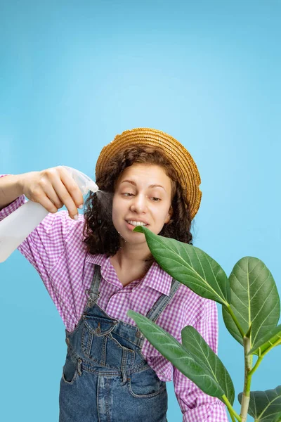 Potret gadis cantik muda, tukang kebun perempuan dalam pekerjaan bunga berseragam berair terisolasi di latar belakang putih. Konsep pekerjaan, emosi, agronomi — Stok Foto