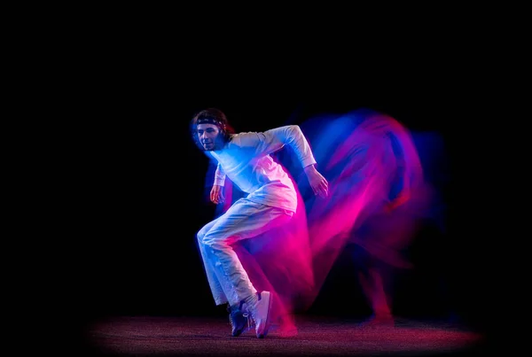 Styl ulice. Muž hip-hop tanečník tanec izolovaný na tmavém pozadí ve smíšeném neonovém světle. Mládež kultura, hip-hop, pohyb, styl a móda, akce. — Stock fotografie