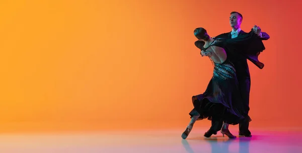 Dans eden çiftli el ilanı, dans eden güzel erkek ve kadın vals, neon ışıkta izole edilmiş turuncu arka planda. Güzellik, sanat, spor konsepti — Stok fotoğraf