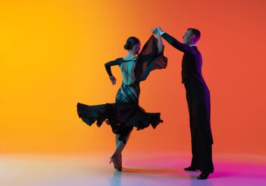 Genç ve güzel bir adamın dinamik portresi dans eden balo salonu dansı gradyan turuncu pembe arka planda neon ışıklarıyla izole edilmiş. Güzellik, sanat, spor konsepti