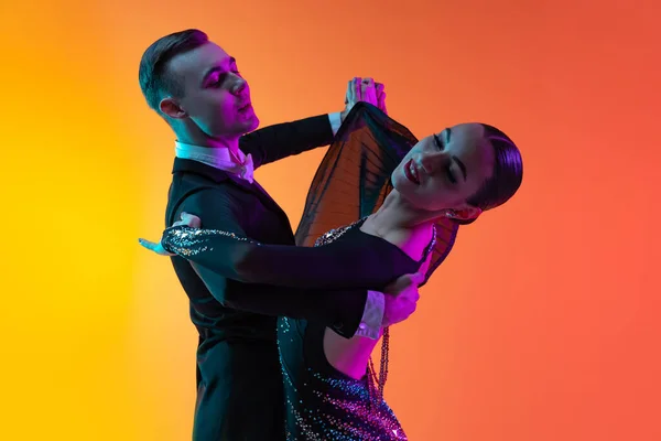 Yakın çekim duygusal dans çifti, dans eden güzel erkek ve kadın vals neon ışıkta izole edilmiş turuncu pembe arka planda. Güzellik, sanat, spor konsepti — Stok fotoğraf