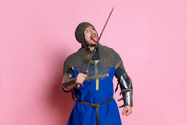 Portret mężczyzny, średniowiecznego wojownika lub rycerza w zbroi z mieczem na różowym tle pracowni — Zdjęcie stockowe