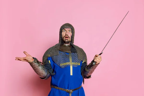Portret mężczyzny, średniowiecznego wojownika lub rycerza w zbroi ochronnej z mieczem ukazującym wstrząśnięty wyraz twarzy — Zdjęcie stockowe