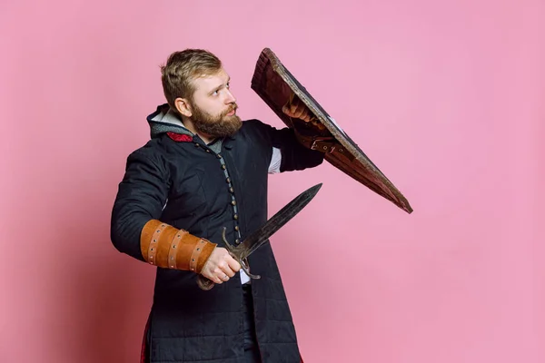 Portré bátor kinézetű ember, középkori harcos vagy lovag láncra fegyverkezve védi magát pajzs elszigetelt rózsaszín stúdió háttér — Stock Fotó