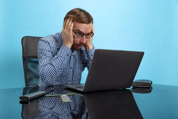 Portrait of man, computer system analyst touching head in shock, working with laptop isolated over blue background — Stock Photo, Image