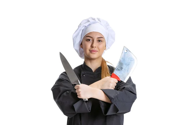 Sonriente joven hermosa, señora cocinera, chef en uniforme negro que sostiene cuchillos de cocina aislados sobre fondo blanco. Cocina, profesión, negocio, comida, gusto, concepto de restaurante. —  Fotos de Stock