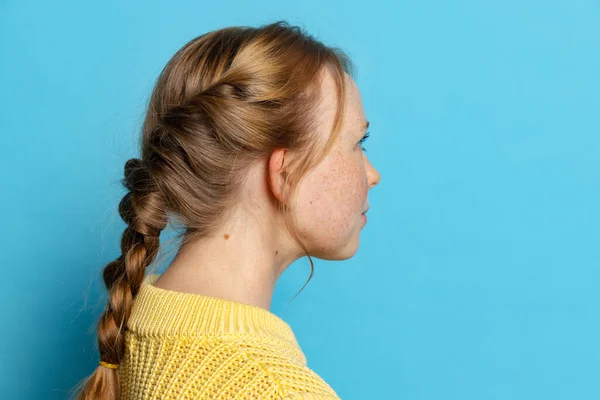 Profile view of young girl in yellow pullover posing isolated on blue background. Concept of emotions, facial expressions — Stock Photo, Image