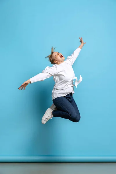 Retrato completo de uma jovem garota excitada pulando isolada no fundo azul. Conceito de emoções wow, expressões faciais, anúncio, vendas — Fotografia de Stock