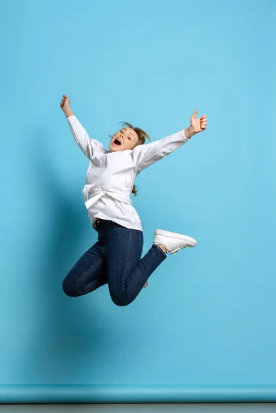 Retrato completo de uma jovem garota excitada pulando isolada no fundo azul. Conceito de emoções wow, expressões faciais, anúncio, vendas — Fotografia de Stock