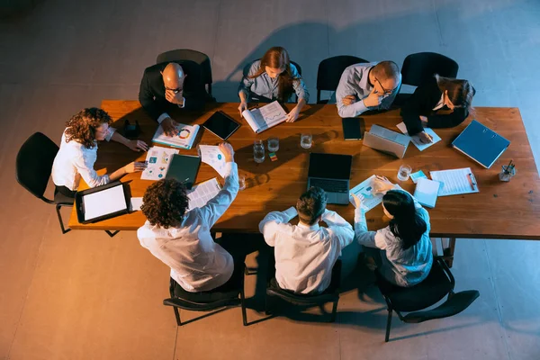 Bij een vergadering. Luchtfoto van jonge multi-etnische mensen die praten, werken met collega 's, collega' s op kantoor, binnen. Werk, financiën, technologisch concept. — Stockfoto