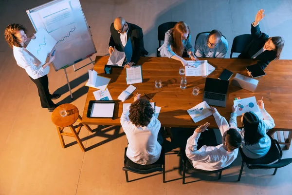 Presentazione del nuovo progetto. Veduta aerea di giovani uomini e donne che parlano, lavorano con colleghi, colleghi di lavoro in ufficio, in casa. Lavoro, finanza, tecnologia. — Foto Stock