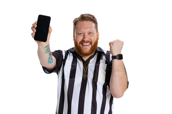 Портрет молодого бородатого чоловіка, футбольного або футбольного арбітра з використанням телефону ізольовано на білому фоні студії. Концепція спорту, правила, змагання, права, реклама, продажі . — стокове фото