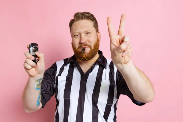 Comic portrait of sport referee wearing field judge uniform isolated on pink studio background. Concept of sport, rules, competitions, rights, ad, sales. — Stock Photo, Image