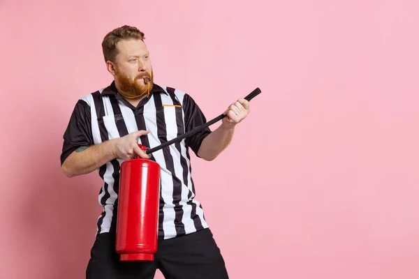 Comic portrait of sport referee wearing field judge uniform isolated on pink studio background. Concept of sport, rules, competitions, rights, ad, sales. — Stock Photo, Image