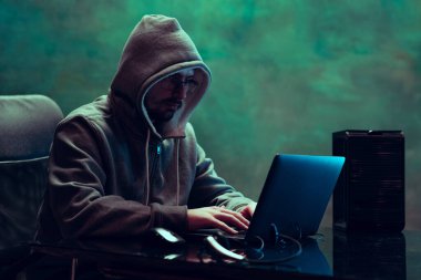 İnsan portresi, profesyonel programcı, güvenlik sistemini kıran web korsanı, neon içinde koyu yeşil arkaplan üzerinden izole edilmiş bilgiler indiriyor.