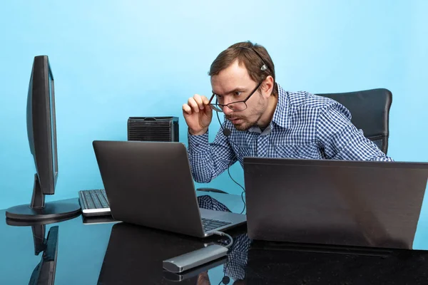 Retrato de homem concentrado, programador, analista de sistema de computador trabalhando com sistema operacional isolado sobre fundo azul — Fotografia de Stock