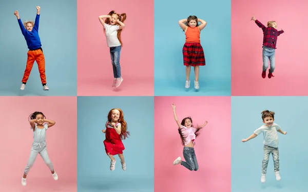 Група учнів початкової школи стрибає в барвистому повсякденному одязі на синьо-рожевому студійному фоні. Креативний колаж . — стокове фото