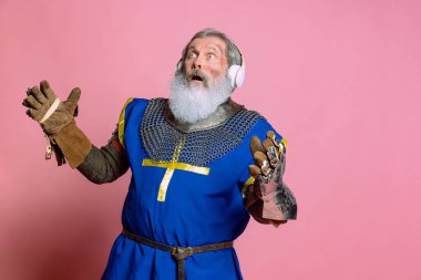 Kıdemli gri sakallı adam, cesur ortaçağ savaşçısı ya da pembe arka planda kılıçlı şövalye. Çağ, tarih, festival karşılaştırması
