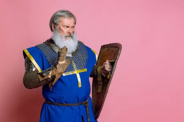 Yaşlı gri sakallı adamın portresi, cesur ortaçağ savaşçısı ya da pembe arka planda kılıçlı şövalye. Çağ, tarih, festival karşılaştırması