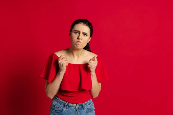 Jeune fille agacée portant des vêtements de style décontracté regardant la caméra isolée sur fond rouge. Concept d'émotions — Photo