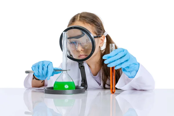 Портрет маленької школярки, дитина в білому великому халаті як хімік, вчений проводить експеримент з різнокольоровою хімічною рідиною в лабораторії ізольовано на білому тлі — стокове фото