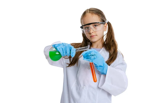 Portrait de petite écolière, enfant en grande robe blanche comme chimiste, scientifique faisant des expériences avec du liquide chimique multicolore en laboratoire isolé sur fond blanc — Photo