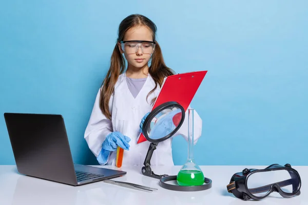 Retrato de niña de la escuela, niño en vestido grande blanco como químico, equipo químico científico, fluido en laboratorio aislado sobre fondo azul — Foto de Stock