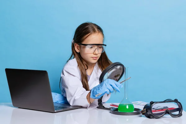 Πορτρέτο του μικρού κοριτσιού σχολείο, παιδί σε λευκό μεγάλο φόρεμα ως χημικός, επιστήμονας χημικός εξοπλισμός, υγρό στο εργαστήριο απομονώνονται σε μπλε φόντο — Φωτογραφία Αρχείου