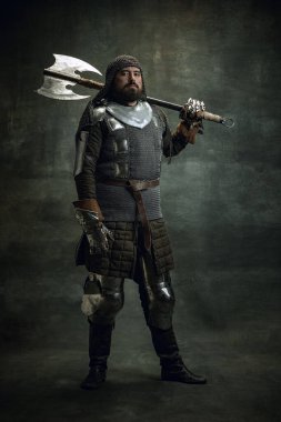 Acımasız bir adamın klasik portresi, Ortaçağ savaşçısı ya da zırhlı yaralı yüzlü şövalye karanlık arka planda izole edilmiş balta tutuyor. Dönem Karşılaştırması