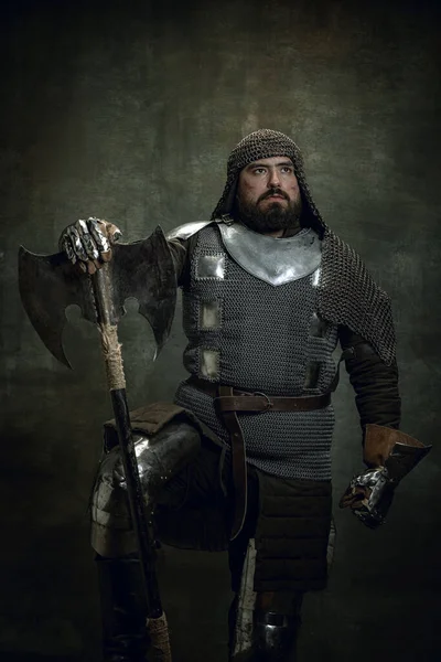 Portrait vintage d'un homme sérieux brutal, d'un guerrier médiéval ou d'un chevalier blessé au visage dans une chaîne de courrier tenant la hache isolée sur un fond sombre. Comparaison des époques — Photo
