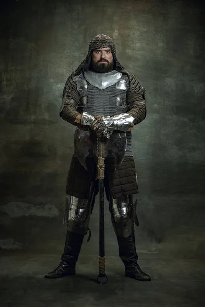 Retrato vintage de seriuos brutais homem, guerreiro medieval ou cavaleiro com rosto ferido em cadeia de correio segurando machado isolado sobre fundo escuro. Comparação de eras — Fotografia de Stock