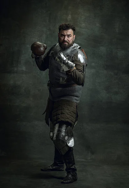 Πορτρέτο του μεσαιωνικού πολεμιστή ή ιππότη με βρώμικα τραυματισμένα γάντια πυγμαχίας πρόσωπο απομονώνονται σε σκοτεινό φόντο. Σύγκριση εποχών, ιστορία — Φωτογραφία Αρχείου