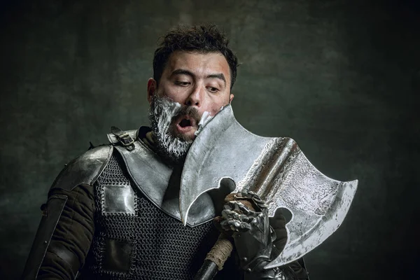 Comic πορτρέτο του μεσαιωνικού πολεμιστή ή ιππότη με βρώμικο τραυματισμένο πρόσωπο ξύρισμα με ένα τσεκούρι απομονώνονται σε σκούρο vintage φόντο. Σύγκριση εποχών, ιστορίας, ομορφιάς — Φωτογραφία Αρχείου
