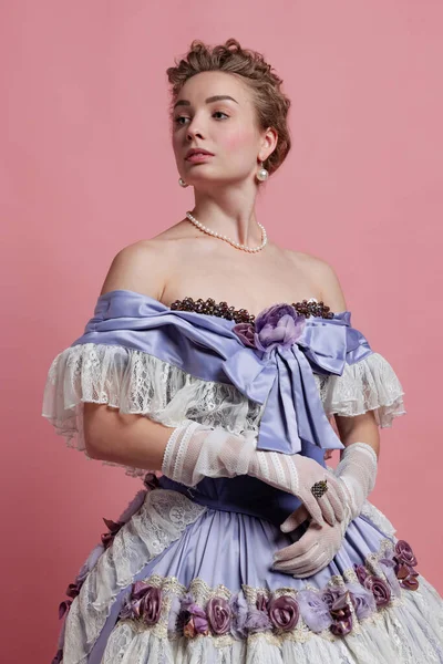 르네상스 풍의 드레스를 입은 중세 왕의 모습을 그린, 귀여운 소녀의 빈티지 초상화가 핑크 색 배경에 고립되어 있다. 시대와 아름다움의 비교 — 스톡 사진