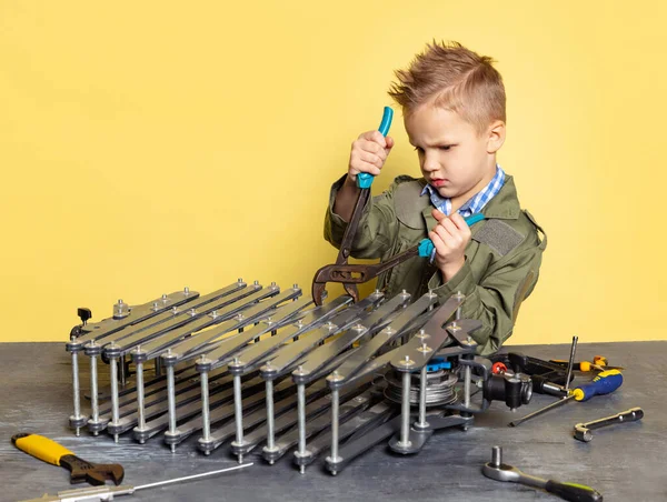 Söt liten pojke, barn i bild av auto mekaniker eller montör i fängelsehålor med arbetsverktyg reparera auto motor isolerad på gul bakgrund. — Stockfoto