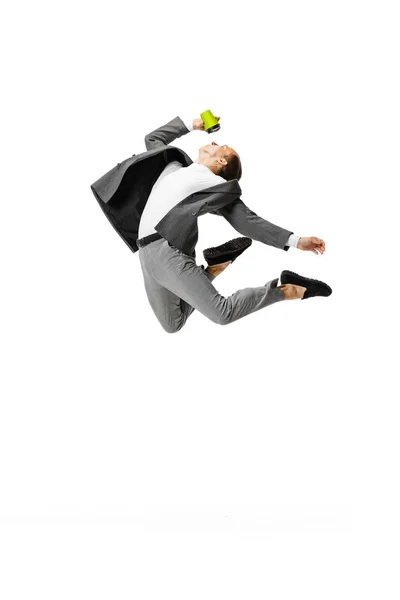 Un joven en traje gris saltando, volando aislado sobre fondo blanco. Negocios, arte, movimiento, acción, creatividad, concepto de inspiración. — Foto de Stock