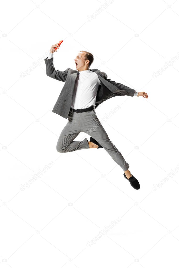 Young man in gray business suit dancing, jumping, flying isolated on white background. Business, art, motion, action, creativity, inspiration concept.