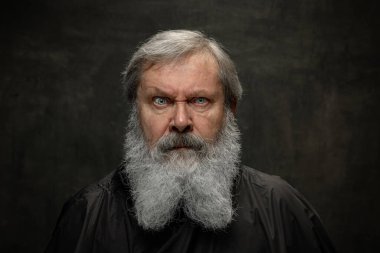 Duygusal yaşlı sakallı bir adamın dramatik portresi. Koyu renkli arka planda sakal tımar ettiriyor. Duyguların kavramı, moda, güzellik, kendini yeniden keşfetme