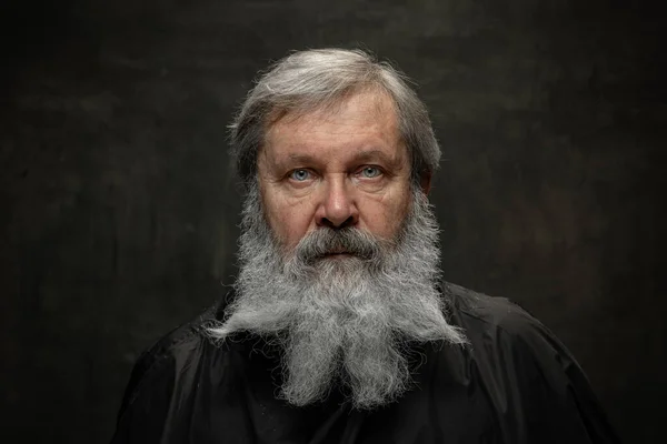 Драматический портрет эмоционального бородатого мужчины, ухаживающего за бородой, изолированного на темном винтажном фоне. Концепция эмоций, моды, красоты, самоизобретения — стоковое фото