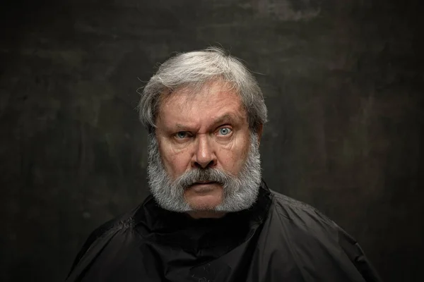 Retrato dramático del hombre barbudo mayor emocional recibiendo barba aseo aislado sobre fondo oscuro vintage. Concepto de emociones, moda, belleza, auto reinvención — Foto de Stock