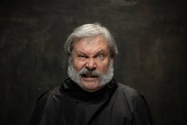 Retrato de un hombre mayor enojado mirando a la cámara aislada sobre un fondo oscuro vintage. Concepto de emociones, moda, belleza, auto reinvención — Foto de Stock