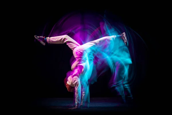 手倒立一个精力充沛、灵活、活泼的年轻人，穿着一身白色衣服，在深蓝色霓虹灯的混合背景下跳嘻哈舞或霹雳舞。运动，艺术，动作，动作 — 图库照片