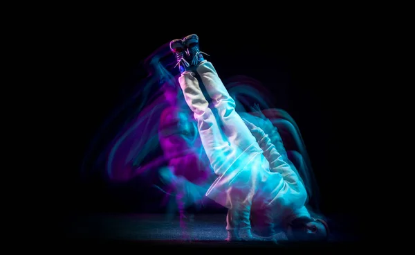 Hand stand. Één energie jonge flexibele sportieve man dansend hip-hop of breakdance in witte outfit op donkere achtergrond in gemengd blauw neon licht. Sport, kunst, actie, bewegingen — Stockfoto