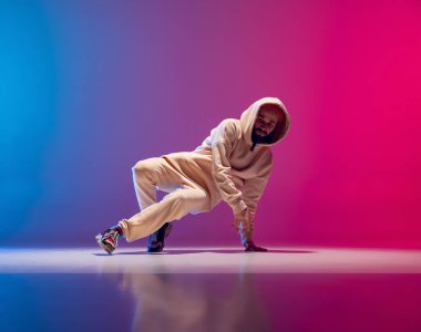 Genç, esnek, sporcu bir adamın gradyan pembe arka planda dans edişinin stüdyo çekimi. Eylem kavramı, sanat, güzellik, spor, gençlik