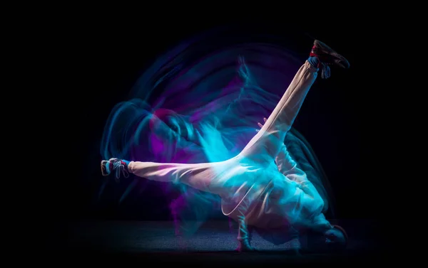 Jedna energie mladý flexibilní sportovní muž tančí hip-hop nebo breakdance v bílém oblečení na tmavém pozadí ve smíšeném modrém neonovém světle. Sport, umění, akce, pohyby — Stock fotografie